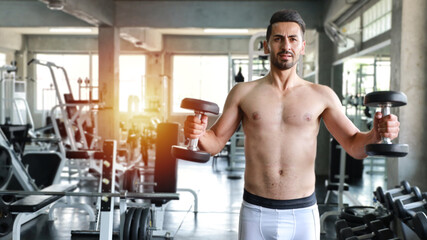 Fototapeta na wymiar Handsome caucasian man with a mustache lifting a dumbbell in fitness with smiling face