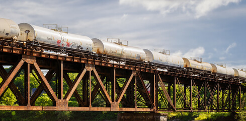 Long line of tanker cars traveling across railroad bridge. blue sky room for copy text.