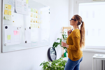 Young businesswoman planning on whiteboard in startup office