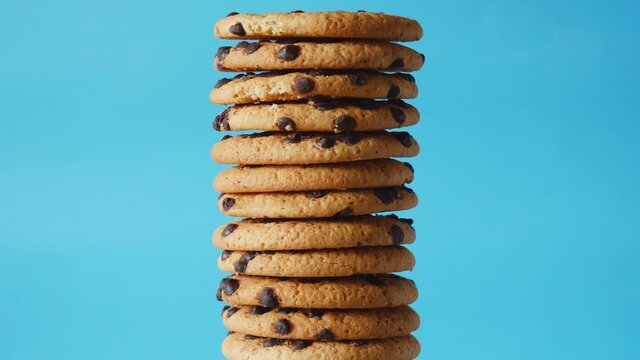 A stack chocolate chip cookies rotate on a blue background. American cookies close up.