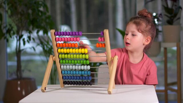 little cute girl play bills home. child is busy play and learn mathematics. childhood and entertainment. Happy family preschool girl at table with multicolored rainbow MULA ikea toy. Toddler Education