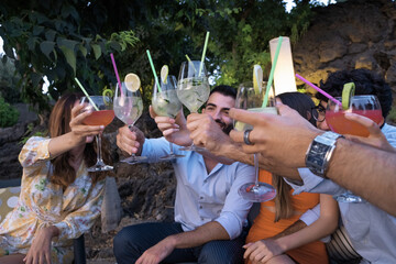 Group of young people who gather on the terrace garden for a cocktail party raising their glasses...