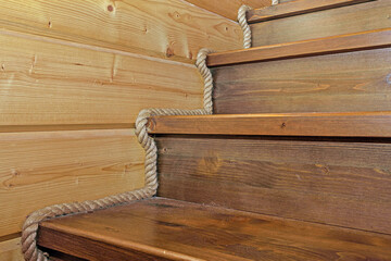 A fragment of a wooden staircase decorated with a rope close-up