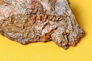 A fragment of a decorative stone on a yellow background close-up