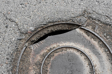 Broken manhole and dirty cracked asphalt