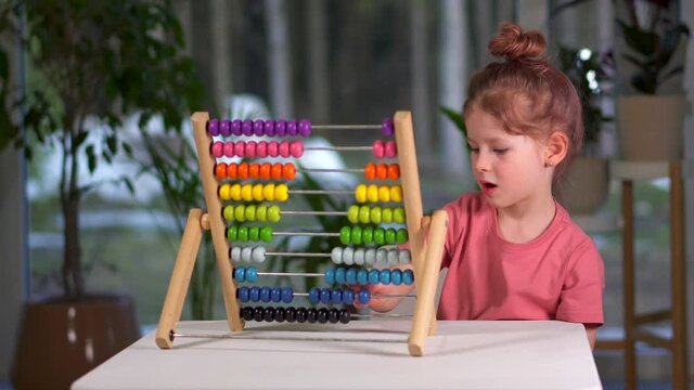 little cute girl play bills home. child is busy play and learn mathematics. childhood and entertainment. Happy family preschool girl at table with multicolored rainbow MULA ikea toy. Toddler Education