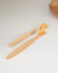 daily human hygiene, cotton swabs and cotton pads, a woman's hand holding bamboo toothbrushes on a light background in a glass or against the background of a wooden tray, eco-friendly personal hygiene