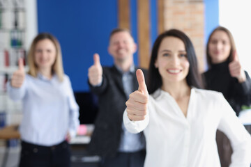 Business leaders with group of employees showing thumbs up