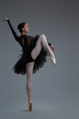 Agile ballerina in black dress against gray background © Fxquadro