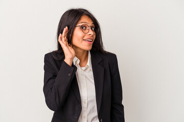 Young business latin woman isolated on white background trying to listening a gossip.