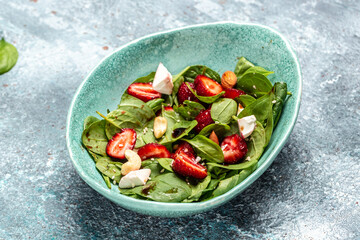Diet menu. Healthy salad of fresh strawberry, spinach leaves, nuts and feta cheese, balsamic vinegar. Vegan food. top view