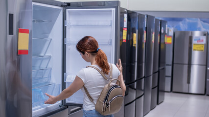 Caucasian woman chooses a refrigerator in a home appliance store