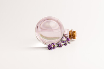 Glass bottle of Lavender essential oil with fresh lavender flowers on white background,...
