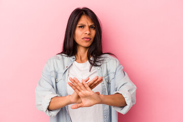 Young latin woman isolated on pink background standing with outstretched hand showing stop sign,...
