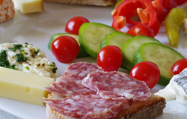 Schön angerichteter Vesperteller mit Salamibrot und Käse samt Gemüsebeilage