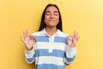 Young mixed race woman isolated on yellow background relaxes after hard working day, she is performing yoga.