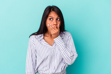 Fototapeta premium Young latin woman isolated on blue background thoughtful looking to a copy space covering mouth with hand.