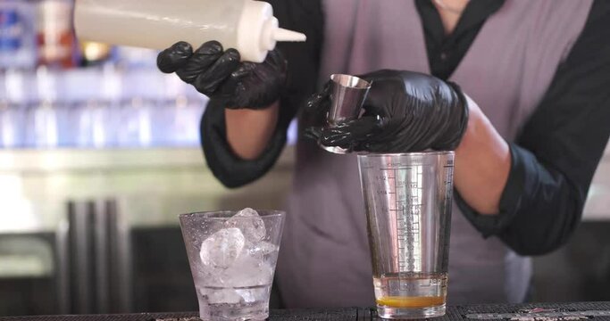 Close up of expert barmanmaking cocktail at night club or bar