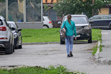 A girl walks through a parking lot on a summer day