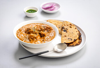 butter chicken gravy served in a white bowl with flatbread roti or naan