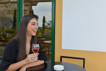 Young woman smiling in the winery. Young girl portrait. Garden background with flowers and trees. Restaurant tables setup. Empty space for text