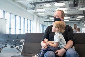 Family father in respiratory mask with a child at the airport waiting for their departure
