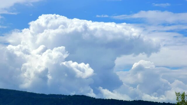 Massive rain clouds, cumulus congestus and cumulonimbus, in the distance above the top of the hill