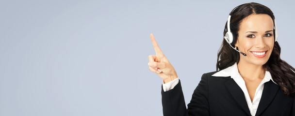 Call center service. Image of customer support phone sales operator in headset showing something or copy space area for text, imaginary or product, over grey colour background. Wide.