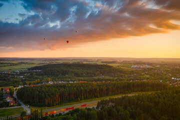 Fototapeta premium Sunset over a forest in Poland with hot air balloons flying in the sky.