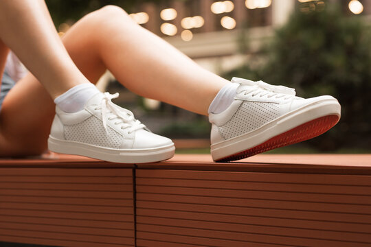 White Perforated Leather Sneakers With Red Sole On The Female Legs