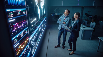 Project Manager and Computer Science Engineer Talk while Using Big Screen Display and a Laptop,...