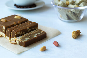 cutting chocolate and milk sherbet with nuts and peanuts on the white table. national traditional sweetness of Turkish and arabic sherbet and halva on the white background. sweet dessert copy space