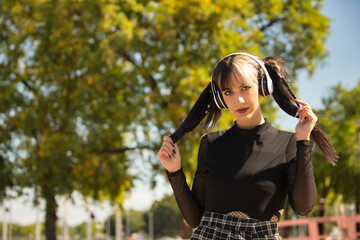 Young and beautiful girl with heterochromia and punk style with white headphones holding her...