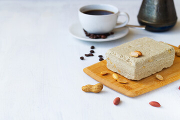 still life with dessert. national traditional sweetness of Turkish and arabic halva with cup of coffee on the white table. halwa from sunflower seeds with peanut on the wood cutting board. copy space