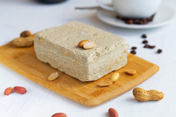 close-up dessert.national traditional sweetness of Turkish and arabic halva with cup of coffee on the white table.piece of halwa prepared from sunflower seeds with peanut on the wood cutting board.