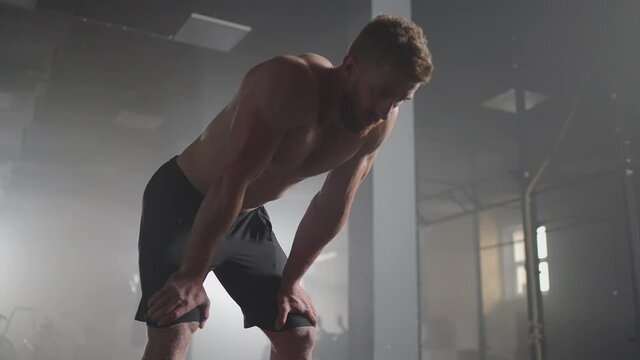 Exhausted young men resting after intensive workout in gym. Fitness healthy man tired after strength training exercise at gym. Tired male fit model with standing and relaxing after intense workout.