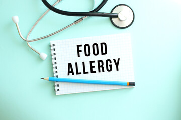 White notepad with the words FOOD ALLERGY and a stethoscope on a blue background.