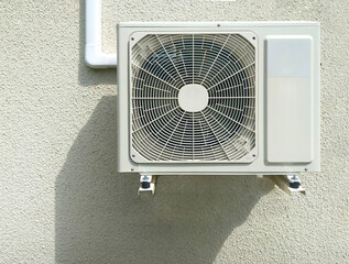 White air source heat pump on a plaster wall