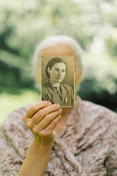Old woman remembers her youth. Grandma keeps her photo in her youth.