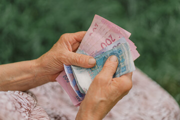 Concerned elderly woman counting Ukrainian money hryvnia.