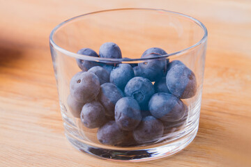 Transparent glass of fresh raw blueberries ready for smoothie.
