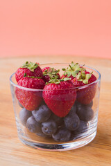 Vertical shot of glass cup of fresh raw blueberries and strawberries.