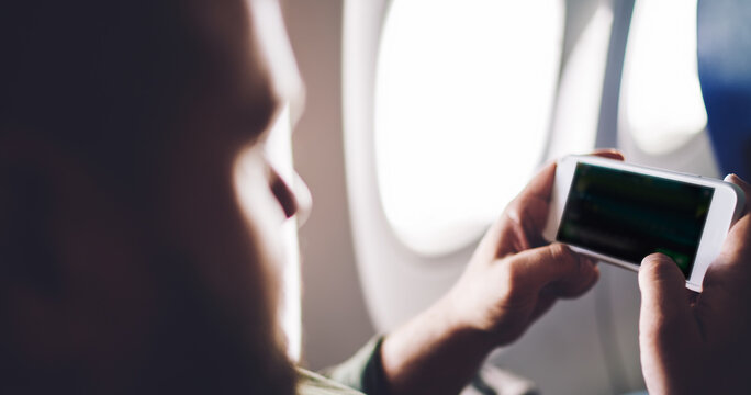 Man watching video on smartphone in plane