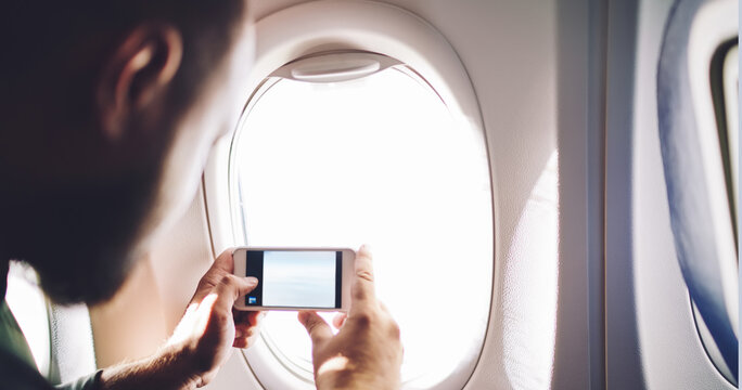 Passenger taking picture through airplane window