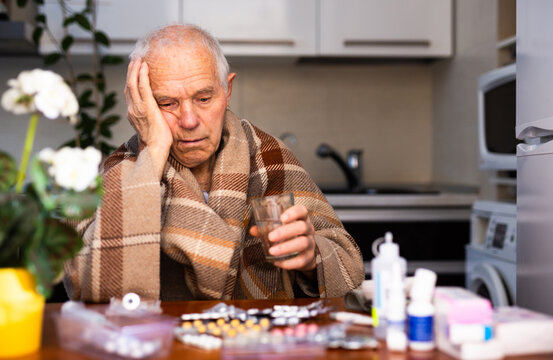 Elderly Senor holding handful of different pills at Home