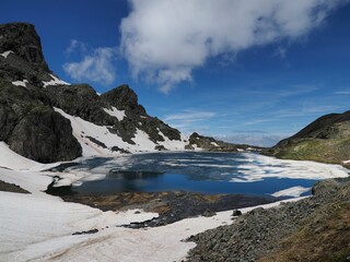 Fototapeta na wymiar lac du petit doménon enneigé, massif de Belledonne. la neige fond et forme des gros glaçons dans le lac.
