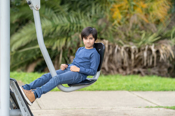 Active kid working out on gym equipment. Fitness concept. Showing healthy lifestyle young boy training at park.