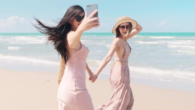 Two Asian women running on the beach Take pictures and have fun together.