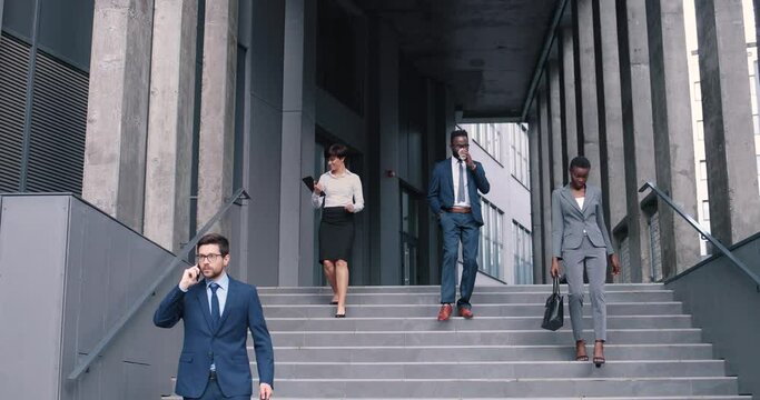 Full of joy. Full length portrait of happy elegant busy business partners are walking along the stairs while feeling satisfied after the work. Business people concept