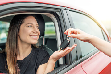 An attractive woman in a car gets the car keys. Rent or purchase of auto - concept.